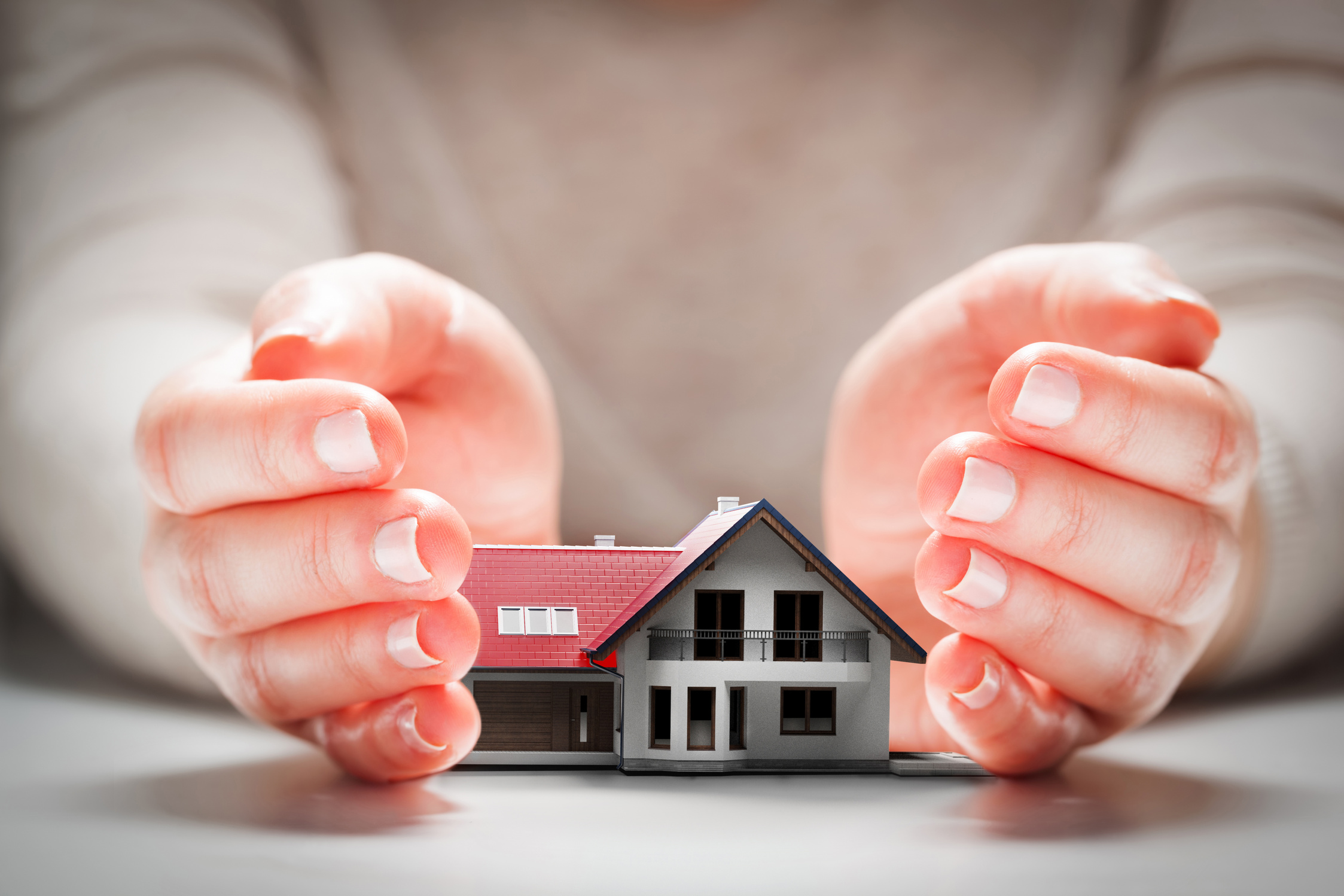 Home insurance, a house model safe in hands